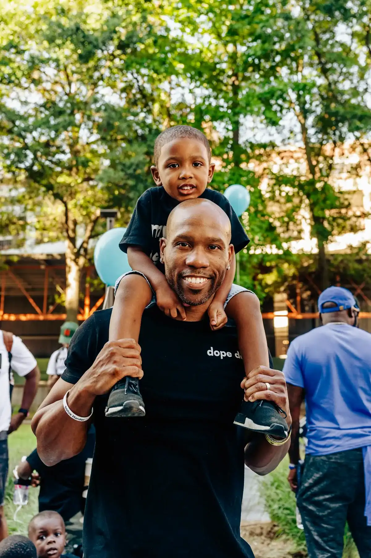 A father carries his son on his shoulders at a Dope Dads gathering